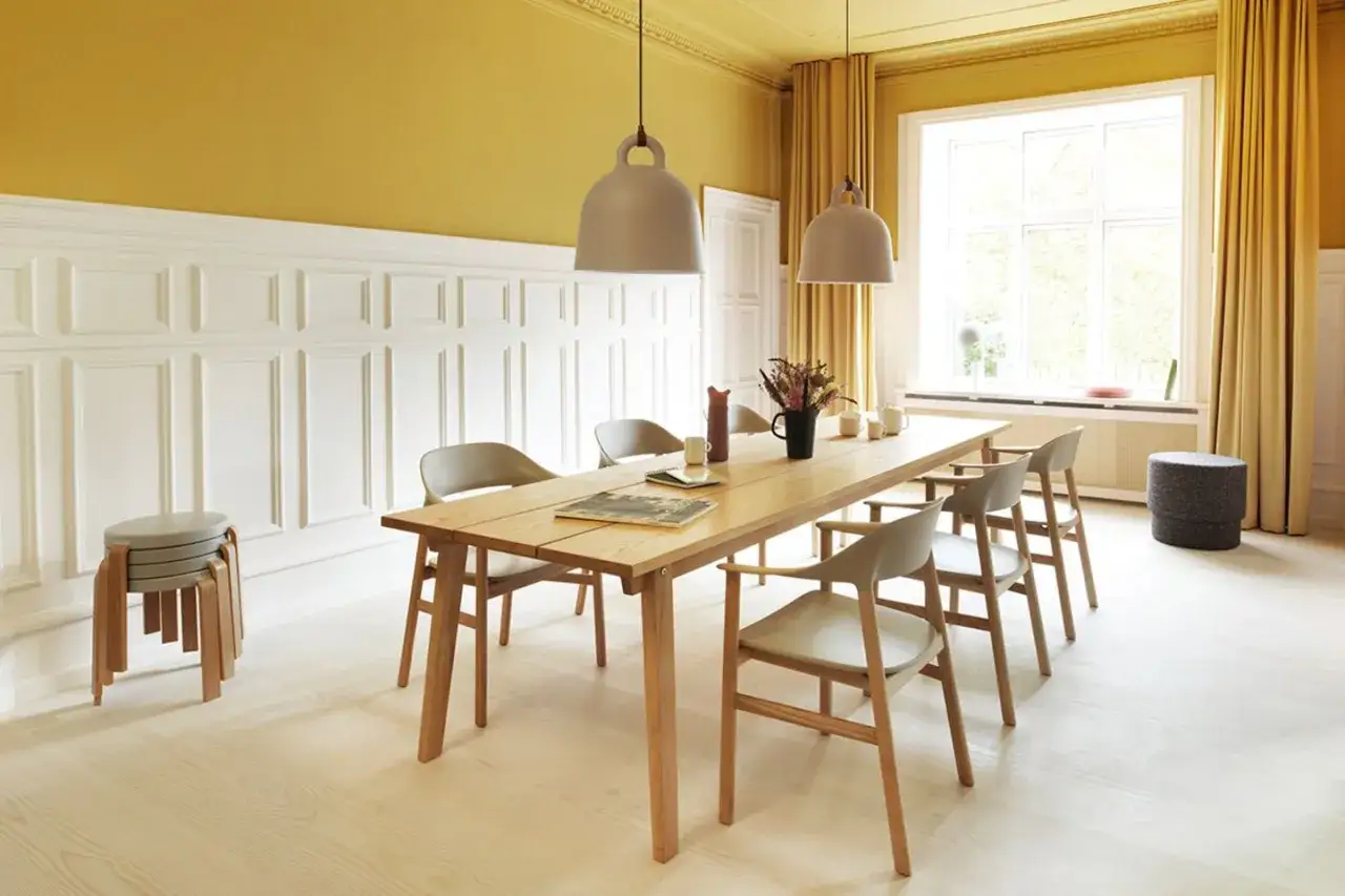 Helle Esszimmer Wand Ideen mit Paneelen und einem Holztisch. Ein sonnengelber Raum mit Vorh&auml;ngen und modernen St&uuml;hlen.