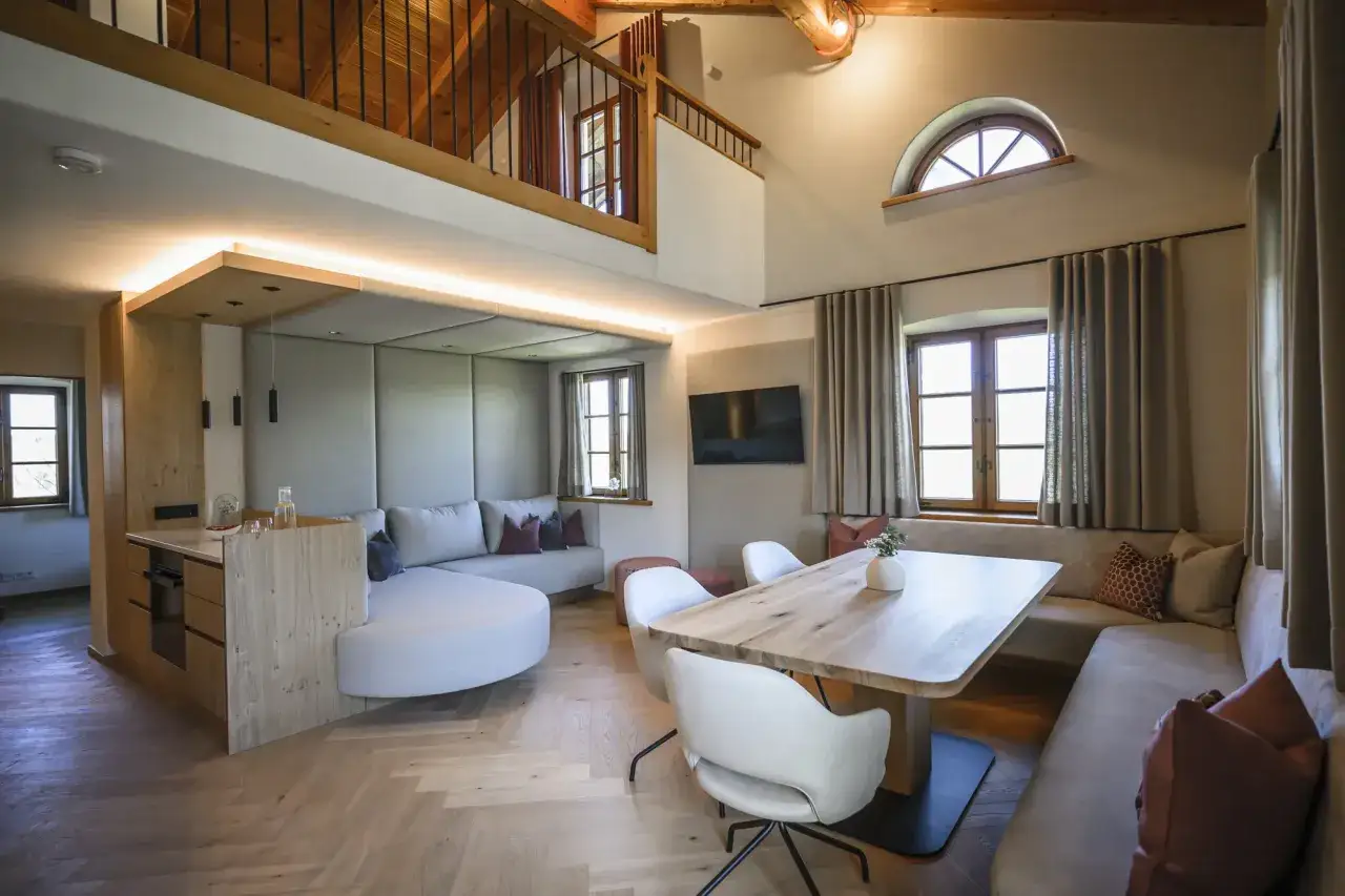 Gem&uuml;tliche Einrichtung einer Ferienwohnung mit Holzboden, bequemer Couch, Essbereich und Galerie.