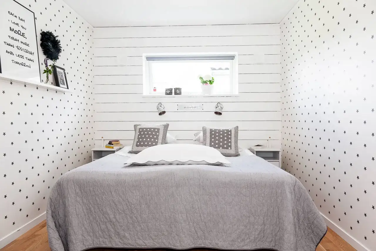 Gemütliches kleines Schlafzimmer einrichten mit Sternen-Tapete und schlichtem Bett.
