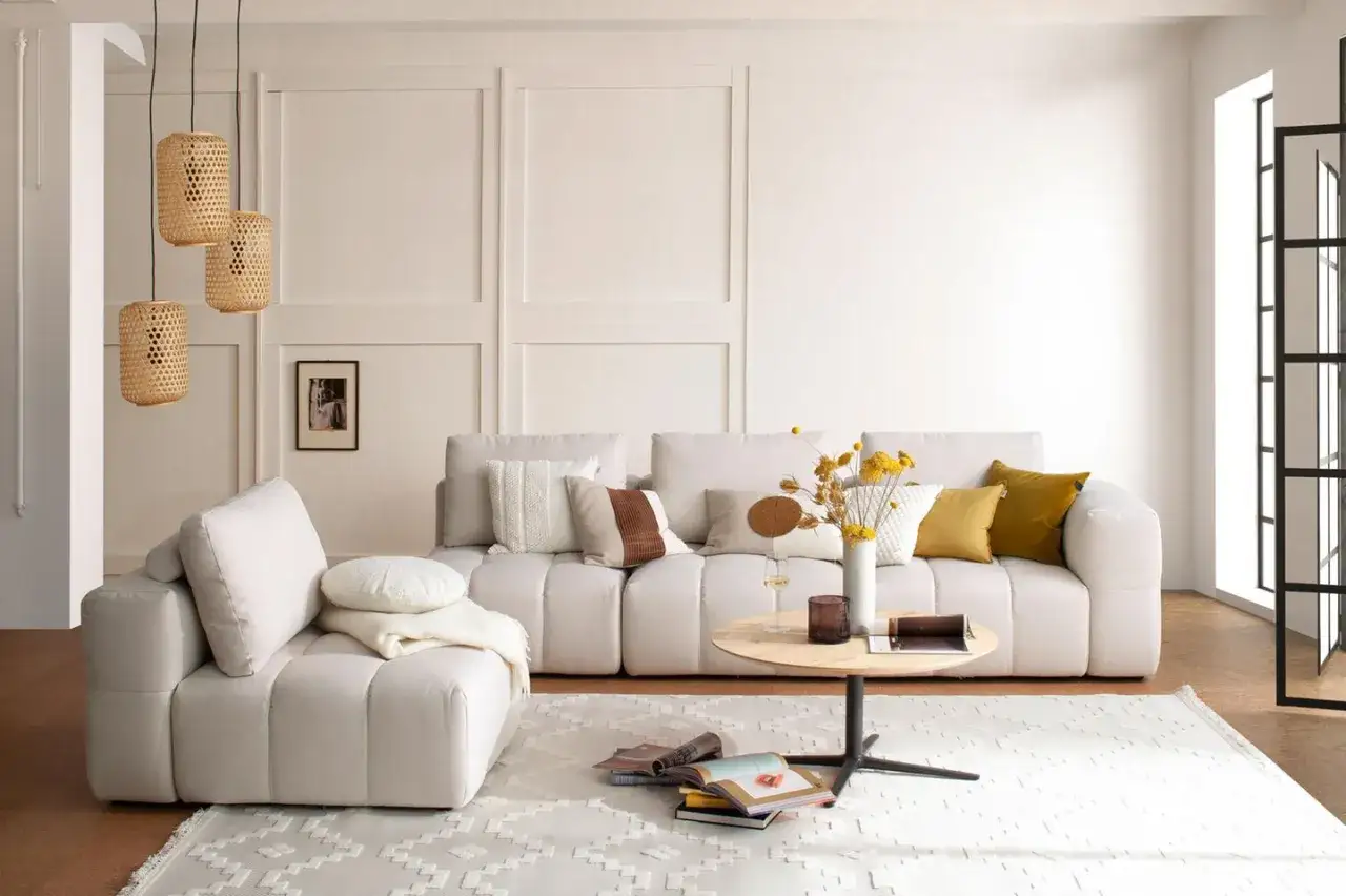 Helle, moderne Wohnzimmereinrichtung mit beigem Sofa, Kissen, Couchtisch und K&ouml;rben, die den Feng Shui Regeln folgen.