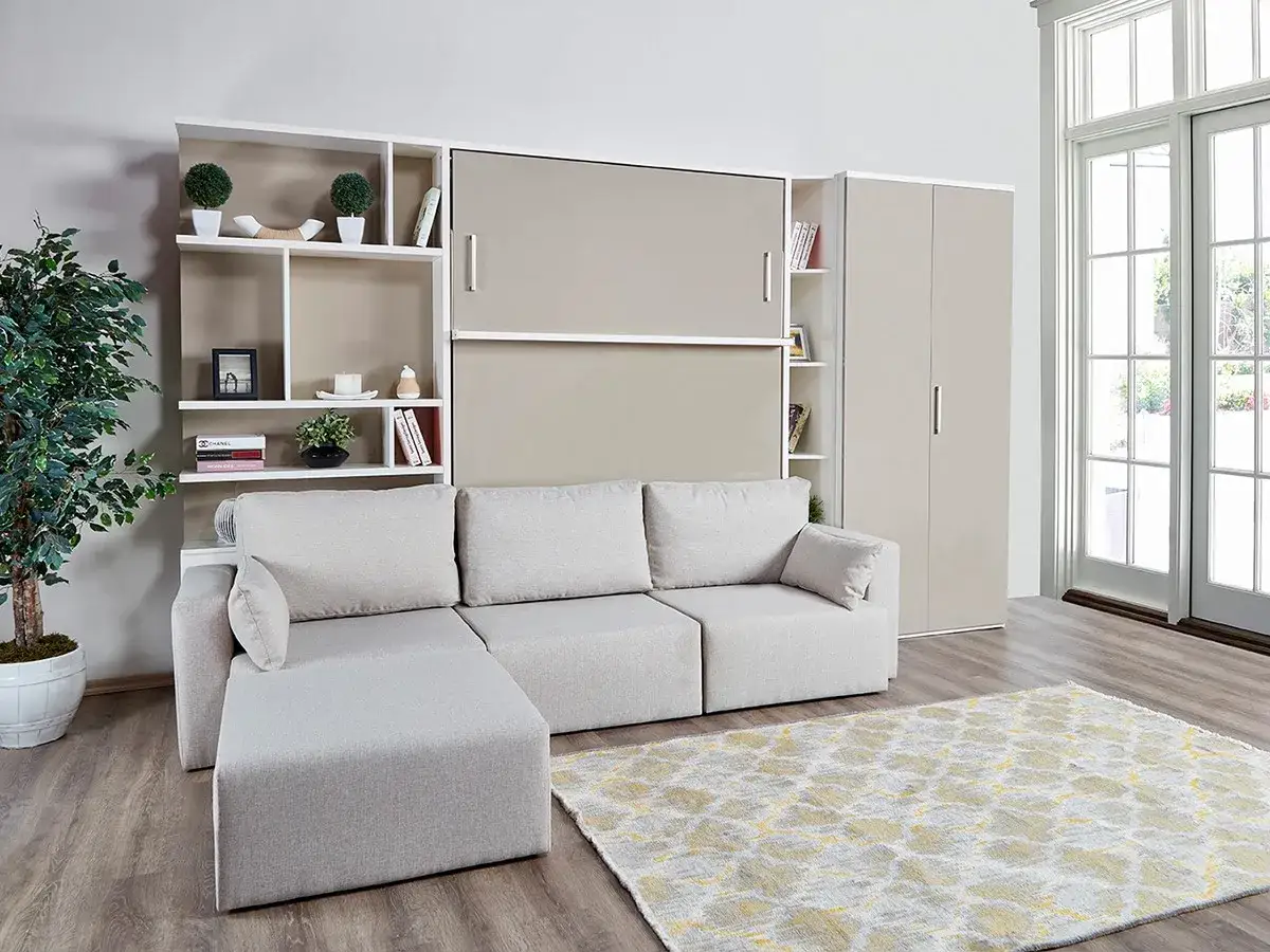 Ein gemütliches Wohnzimmer mit Sofa und einem cleveren versteckten Bett im Schrank. Bücherregale und eine Pflanze schmücken den Raum.