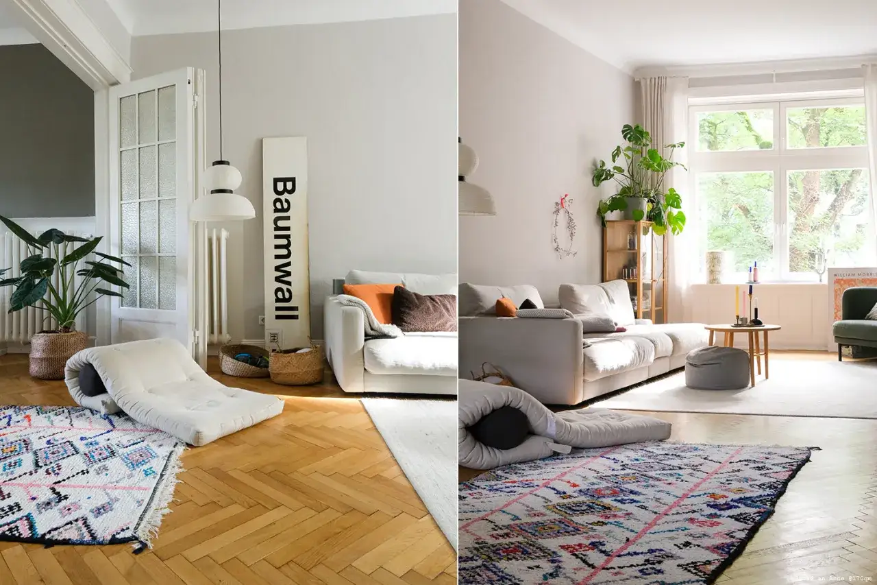 Gemütliches Wohnzimmer in greige farbe mit weißen Sofas, bunten Teppichen und viel Grün.