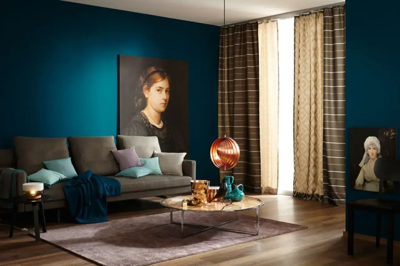 Ein Wohnzimmer mit petrolfarbenen Wänden. Welche Farbe passt zu petrol? Hier Braun und Beige als Akzente.