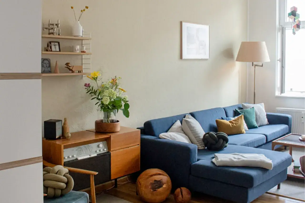 Ein blaues Sofa mit Kissen in Gelb, Gr&uuml;n und Grau. Die Frage, welche Farbe passt zu Blau, wird hier stilvoll beantwortet.