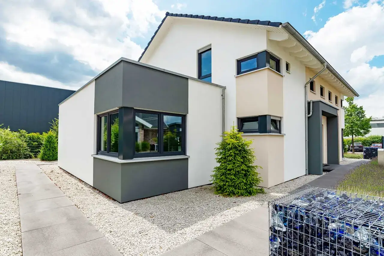 Modernes Haus mit anthrazitfarbenen Kunststofffenstern, die einen stilvollen Kontrast zur wei&szlig;en Fassade bilden.
