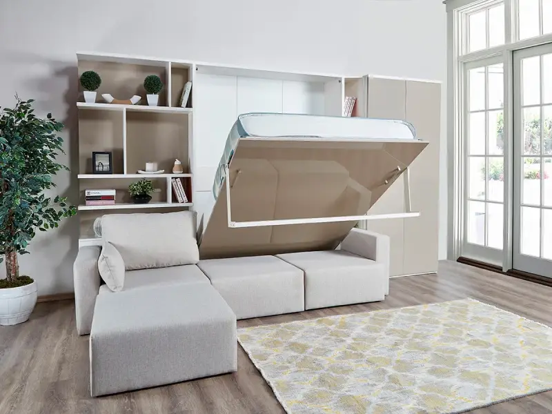 Ein verstecktes Bett im Wohnzimmer wird aus einem Schrank herausgeklappt. Daneben ein Sofa und ein Bücherregal.